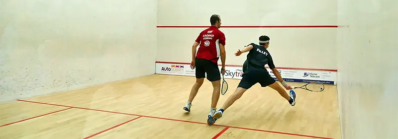 Two professional squash players in the. middle of a tough rally