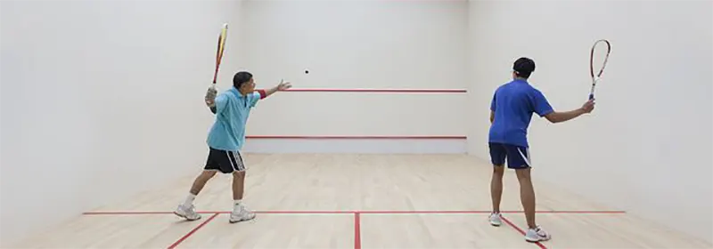 Two men playing squash in coloured shirts