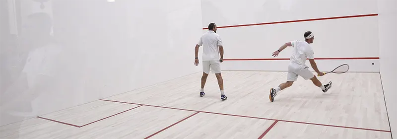 Two men playing squash in white shirts